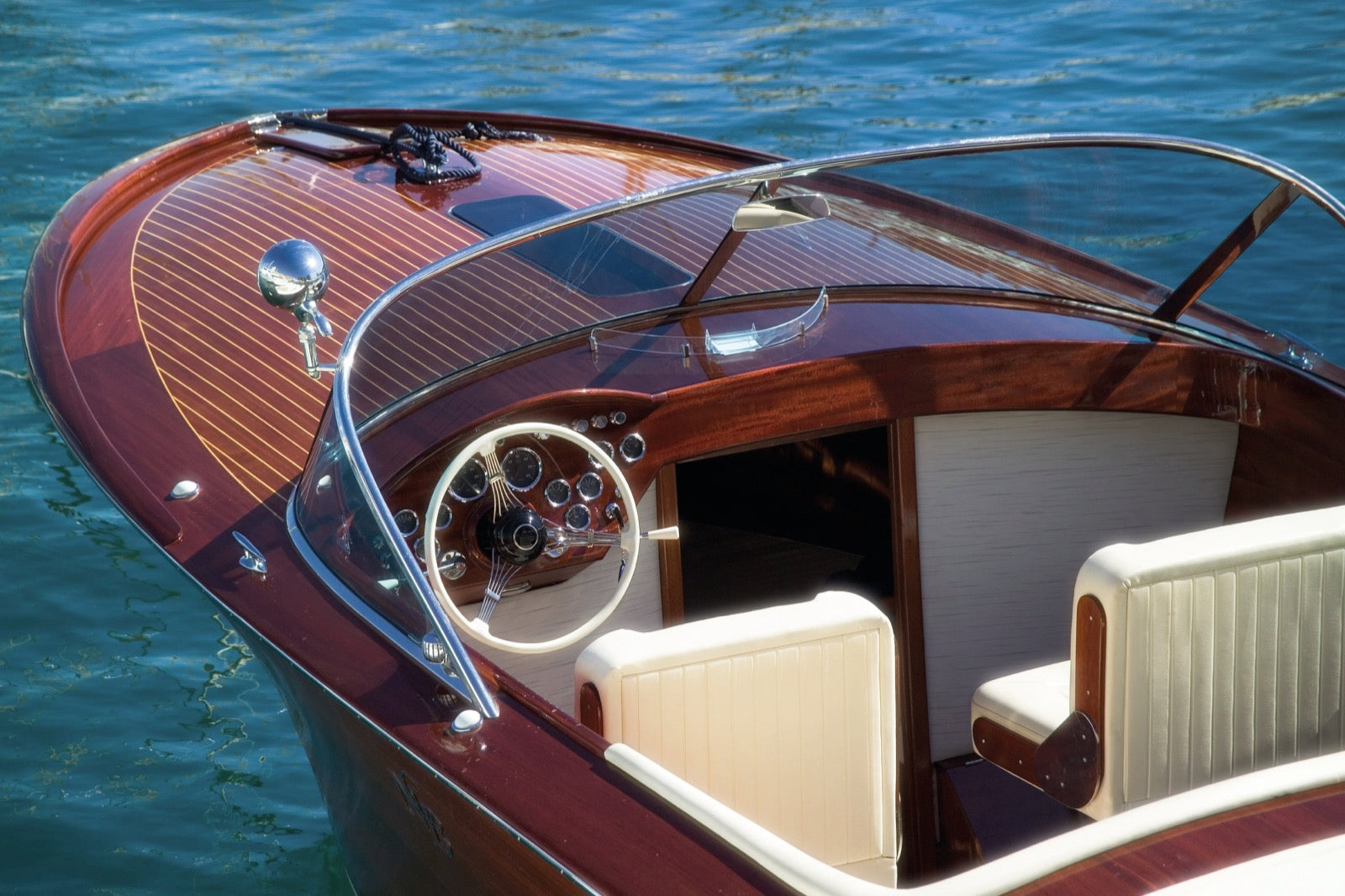 Elegantes Motorboot mit glänzendem, lackiertem Holzdeck auf blauem Wasser - Beispiel für professionellen Bootslack
