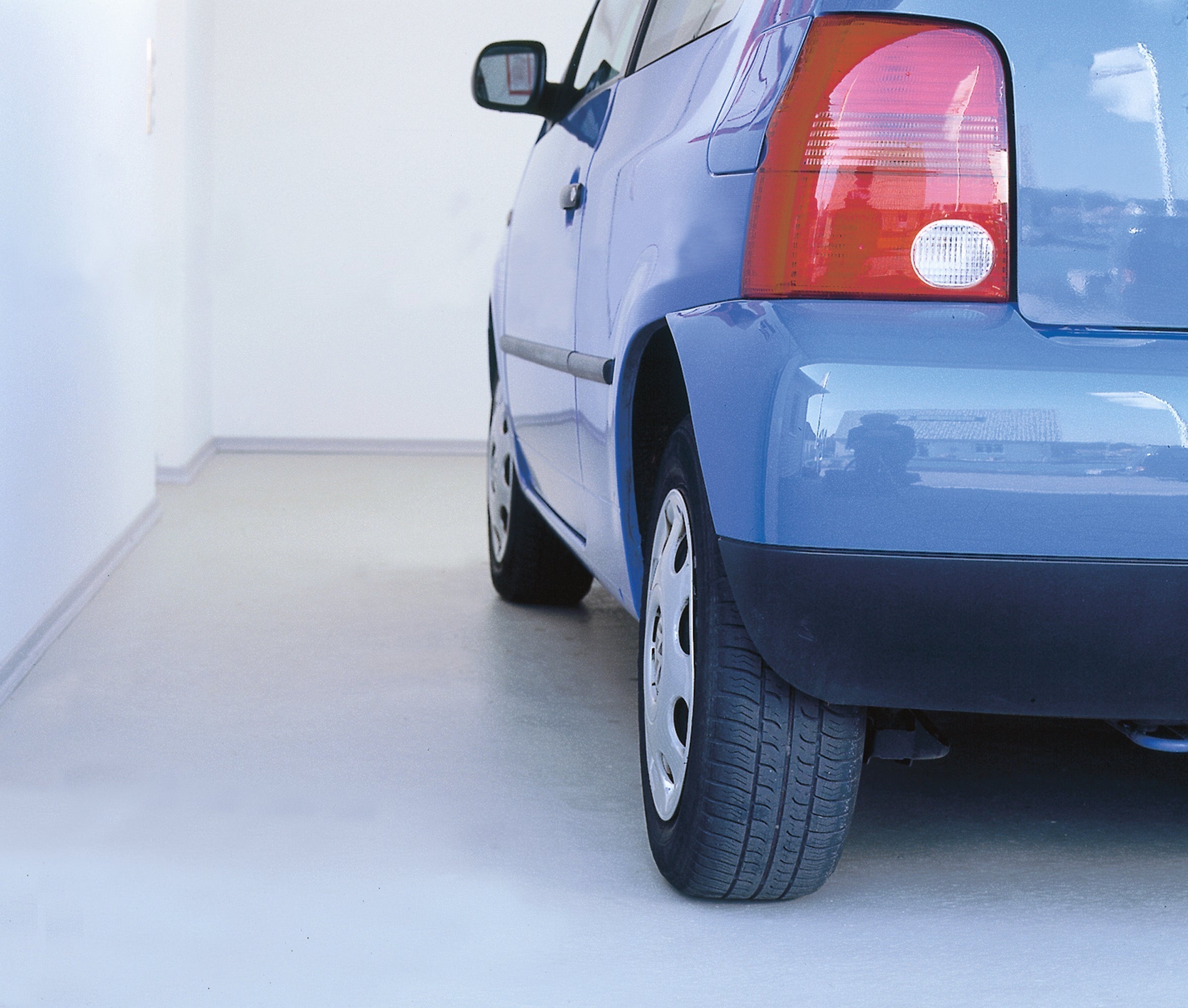 Blaues Auto in moderner Garage mit heller, beschichteter Bodenfläche - Beispiel für professionelle Garagenbodenbeschichtung