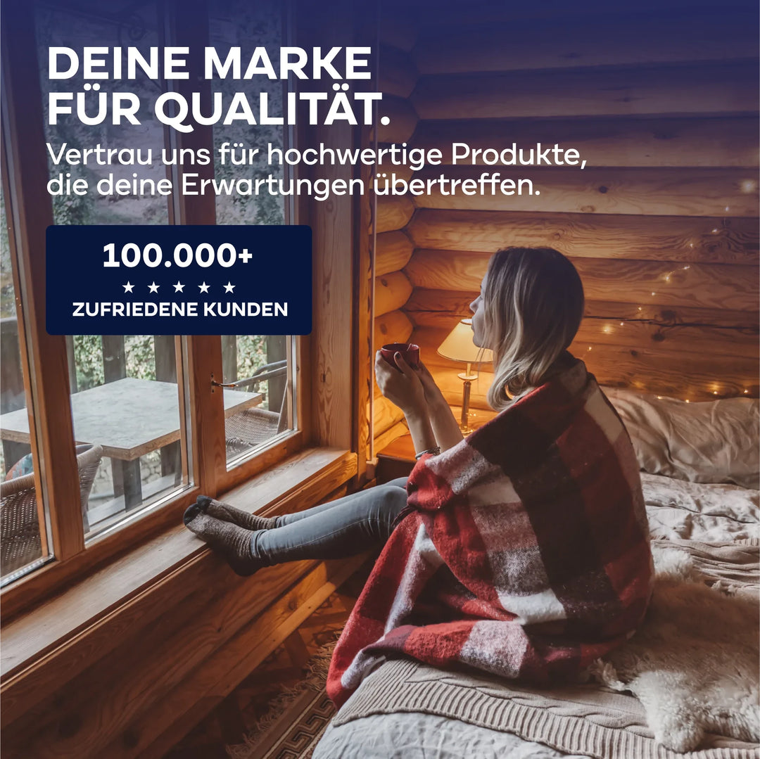 Eine Frau in einer rotkarierten Decke sitzt auf einem Bett in einer gemütlichen Holzhütte und blickt aus dem Fenster. Deutscher Text wirbt für plid Holzwurm Schreck - Anstreichset, dem Holzschutz von über 100.000 zufriedenen Kunden vertraut.