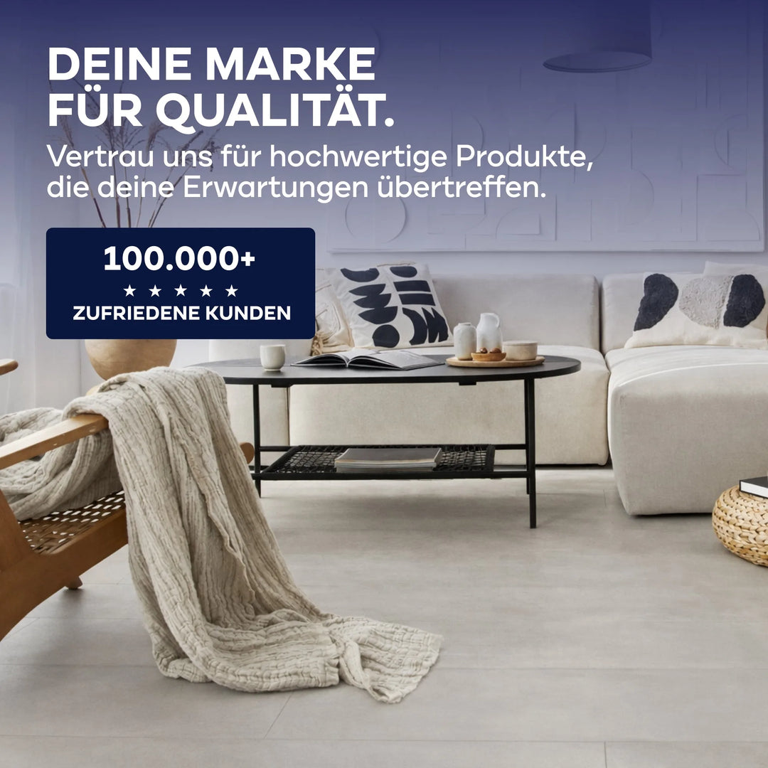 Modernes Wohnzimmer mit beigem Sofa, schwarzem runden Couchtisch und hellem Holzstuhl mit Strickdecke. Entdecken Sie plid&