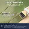 Eine Hand trägt plid Plid Wetterschutz Holzfarbe - deckend & wetterfest für innen & außen auf, eine deutsche, hochwertige Holzfarbe auf Wasserbasis mit seidenmattem Finish und langanhaltendem Wetterschutz, die die einfache Verarbeitung hervorhebt.