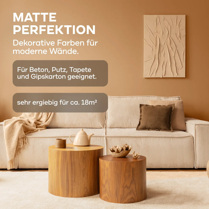 Beiges Wohnzimmer mit heller Couch, braunen Kissen, runden Holztischen und abstrakter Kunst. Die plid DesignColour Innenfarbe - Emissionsarm &amp; Geruchsneutral ist matt, reicht für ca. 18 m² und eignet sich für verschiedene Oberflächen.