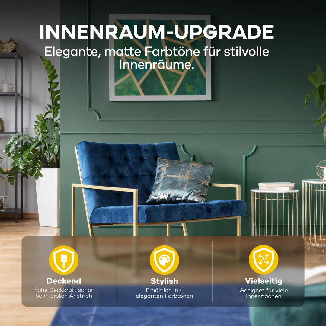 Ein modernes Wohnzimmer mit einer dunkelgrünen Wand in plid DesignColour Innenfarbe - Emissionsarm &amp; Geruchsneutral, blauem Samtsessel, gemusterten Kissen, goldenen Akzenten, Pflanzen und Regalen. Matte Töne sind vielseitig und emissionsarm für stilvolle Innenräume.