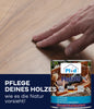 Eine Hand berührt eine glatte Hartholzoberfläche. Unten sehen Sie eine Dose plid Holzöl natürlich & pflegend für Holz innen & außen, mit Produktinformation und dem deutschen Text: Pflege deines Holzes wie es die Natur vorsieht! Ideal für Gartenmöbel.