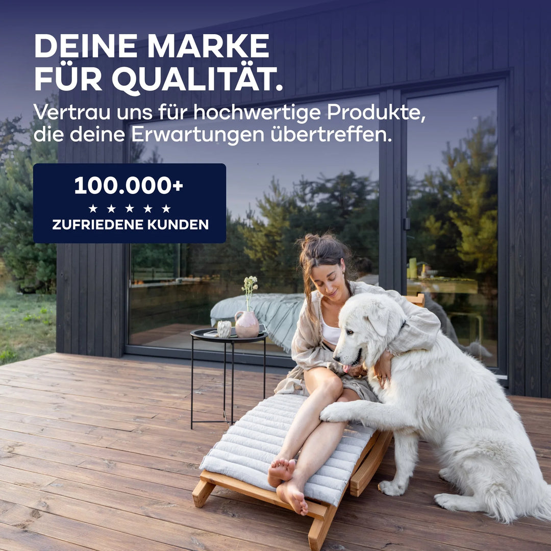 Eine Frau entspannt sich in einem Liegestuhl und streichelt ihren weißen Hund auf einer Holzterrasse. Hinter ihr ist ein modernes Haus mit Glastüren zu sehen, das plid Plid® Möbellack Innen &amp; Außen präsentiert, dem mehr als 100.000 zufriedene Kunden bei Möbel &amp; Holz vertrauen.