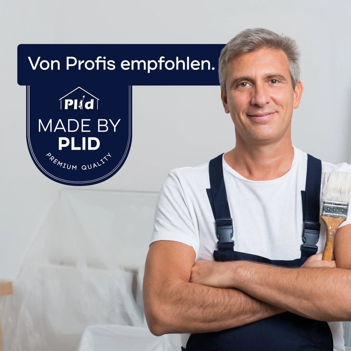 Ein lächelnder Mann in Latzhose mit einem Pinsel steht neben einem Schild: Von Profis empfohlen. MADE BY PLID PREMIUM-QUALITÄT. Der Hintergrund suggeriert Renovierungsarbeiten mit plid Abdeckvlies 220 g/m² für zuverlässigen Oberflächenschutz.