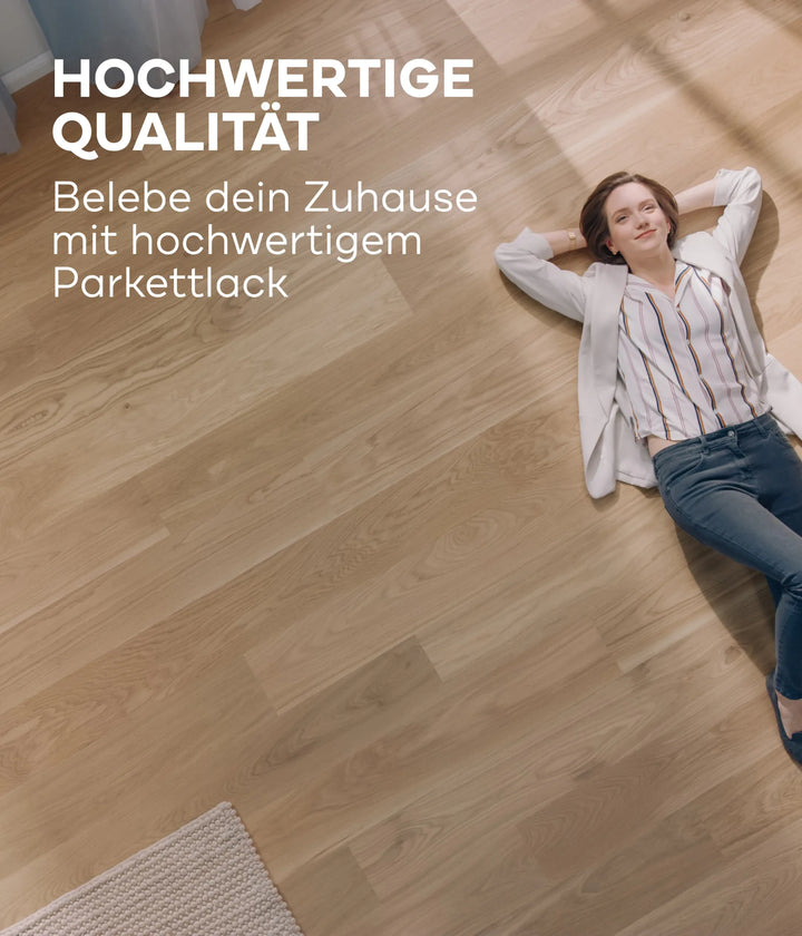 Eine Frau in legerer Kleidung entspannt sich auf einem sonnenbeschienenen Holzboden und lächelt. Der plid Parkettlack Anstreichset glänzend / Satin für Holzböden verleiht den Holzoberflächen einen brillanten Glanz, wie im deutschen Text über diesen Premium-Lack hervorgehoben wird.