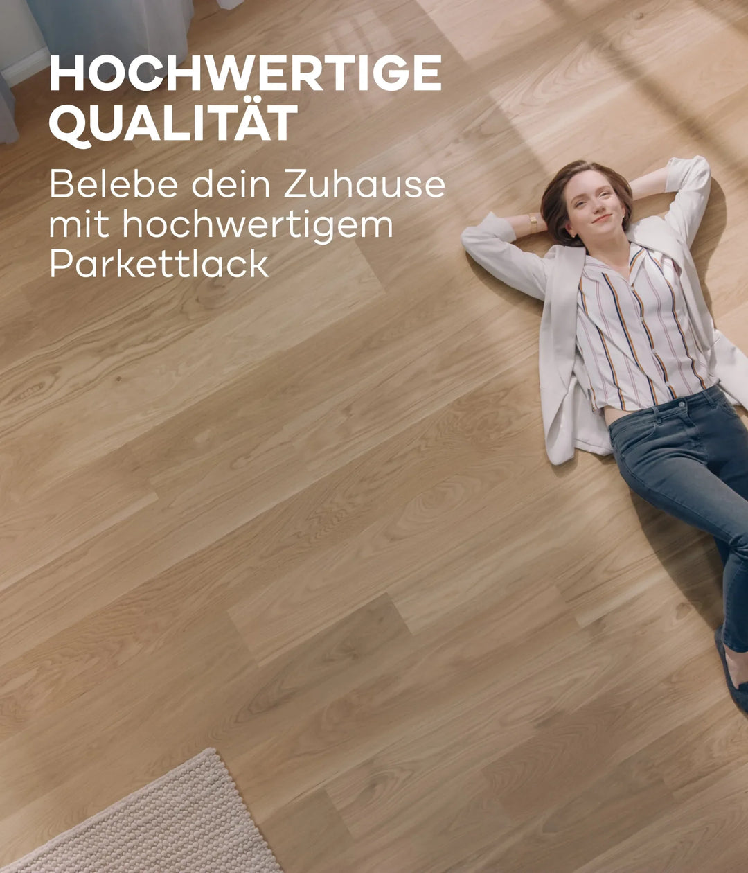 Eine Frau in legerer Kleidung entspannt sich auf einem sonnenbeschienenen Holzboden und lächelt. Der plid Parkettlack Anstreichset glänzend / Satin für Holzböden verleiht den Holzoberflächen einen brillanten Glanz, wie im deutschen Text über diesen Premium-Lack hervorgehoben wird.