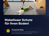 Eine Frau liegt auf dem Rücken auf dem Boden eines modernen Wohnzimmers und kuschelt mit einem großen weißen Hund. Der Raum ist mit minimalistischen Möbeln und großen Fenstern ausgestattet. Der Text auf Deutsch wirbt für einen langlebigen, schützenden Bodenbelag.