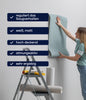 Eine Frau steht auf einer Trittleiter und klebt blaue Tapeten auf eine weiße Wand. Aufgelisteter deutscher Text hebt plid Plid Tapetengrund - haftvermittelnd & saugausgleichend für Innen: regulierte Saugfähigkeit, weiß-matt, hohe Deckkraft, atmungsaktiv, ideal zur Untergrundvorbereitung.
